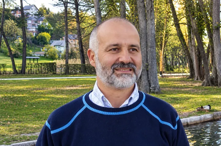 Iuri Silvestri smiling in a lakeside park with trees behind him